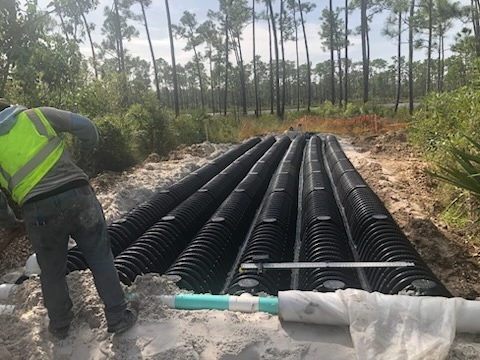 Worker checking the level on a newly installed septic tank drain field and PVC distribution pipe
