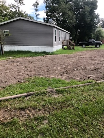 Freshly graded dirt covering a newly installed septic drain field next to a mobile home