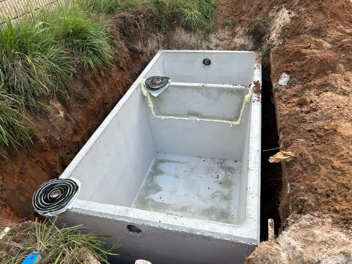 New two chamber precast concrete grease interceptor set in an open trench with butyl sealant rope on the riser collars