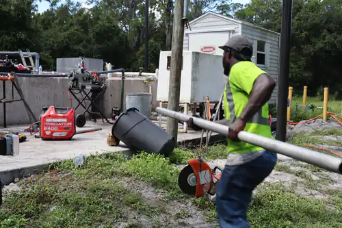 Centrel Services technician carrying a length of new galvanized pipe across the plant site