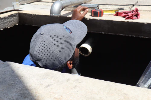 Technician looking down into a treatment basin opening with a tape measure on the rim