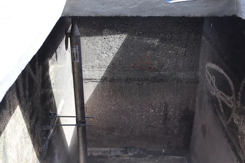 New drop pipe clamped to the inside wall of a concrete treatment basin