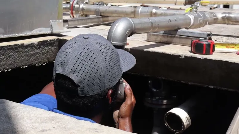 Crew member at the basin opening working on a galvanized elbow below the rim